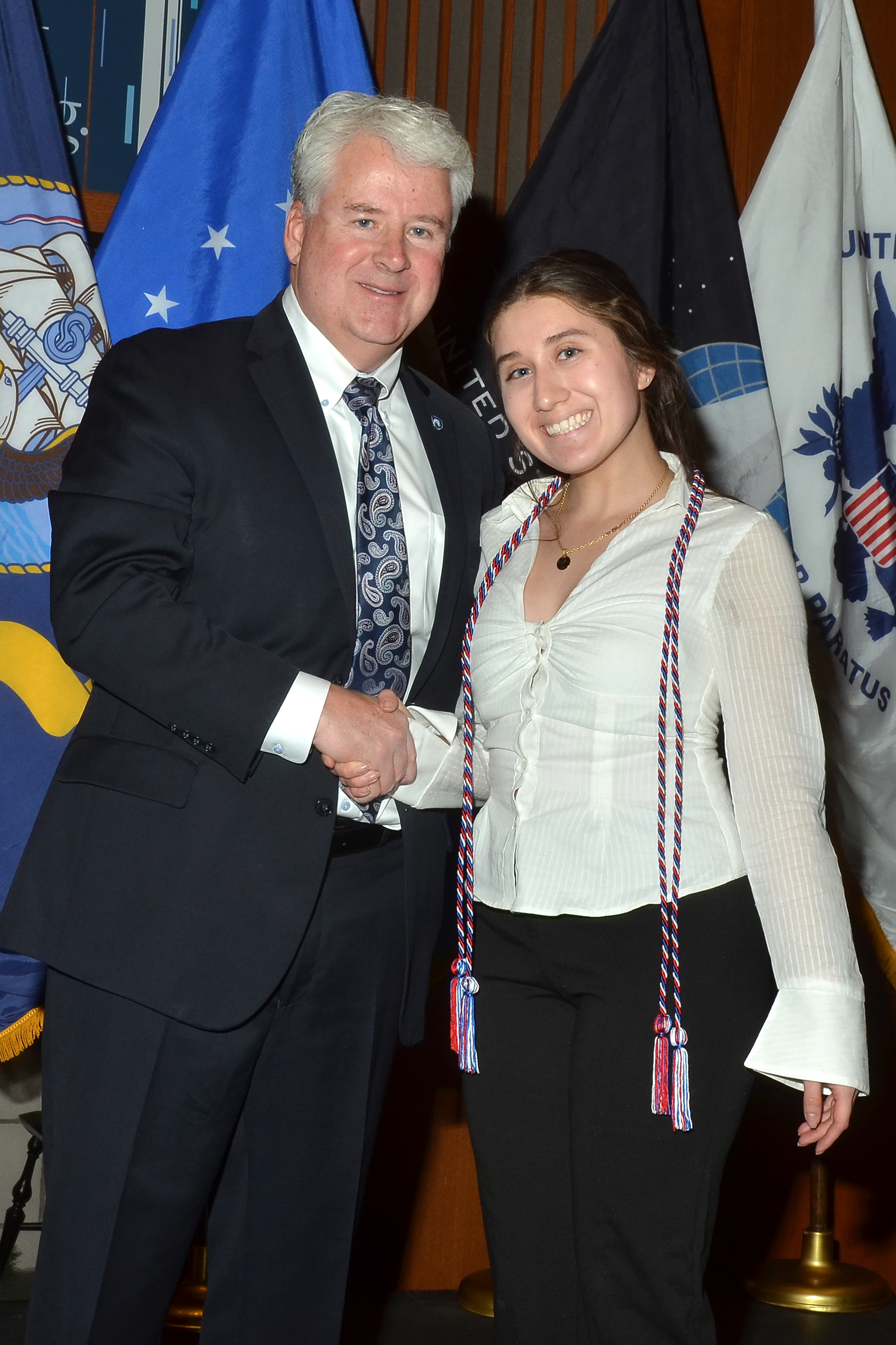 Image of Allan Sonsteby shaking hands with recent female graduate wearing honor cord.